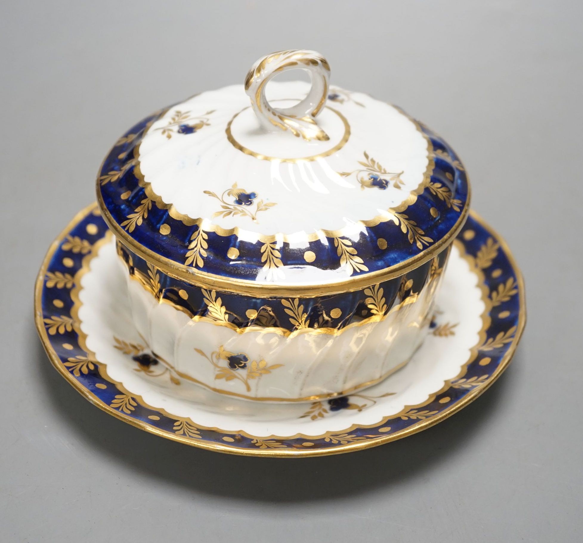 A Chamberlain fine and rare wrythen double tram moulded butter tub, cover and stand decorated in under-glaze blue and gilt c.1800, 12 cms high.